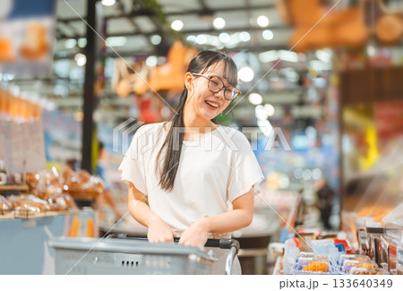 Young adult asian woman consumer choosing ready meals cooked food at supermarket store choice buying 133640349