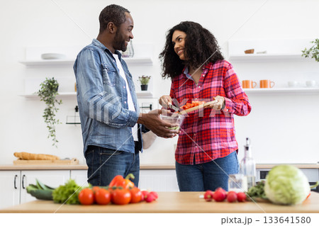 A smiling couple prepares a meal together in a bright, modern kitchen, filled with fresh ingredients. A smiling couple prepares a meal together in a bright, modern kitchen, filled with fresh ingredients. 133641580