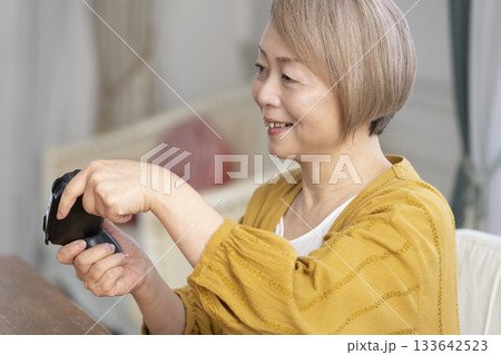 リビングでテレビゲームを楽しむシニア女性 リビングでテレビゲームを楽しむシニア女性 133642523
