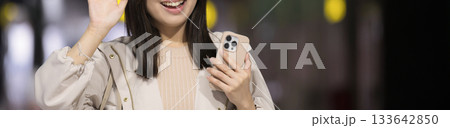 夜の都会の駅や空港、バスターミナルでスマホを見る女性の通勤帰宅シーンと都会のライフスタイル 133642850