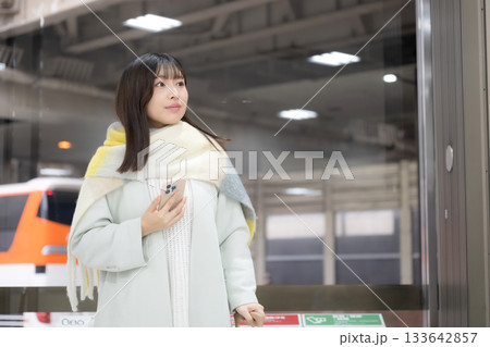冬の駅のホームやバスターミナルなどでスマホを持つ女性 手を振る 冬の駅のホームやバスターミナルなどでスマホを持つ女性 手を振る 133642857