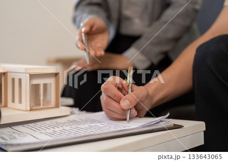 Real estate agent assisting client with paperwork and model home 133643065