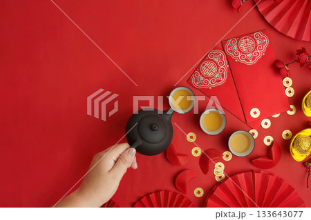 Pouring tea for Lunar New Year celebration with red envelopes Pouring tea for Lunar New Year celebration with red envelopes 133643077