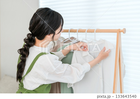 洋服をハンガーにかけてハンガーラックに吊るす家事をする主婦のアジア人女性 洋服をハンガーにかけてハンガーラックに吊るす家事をする主婦のアジア人女性 133643540