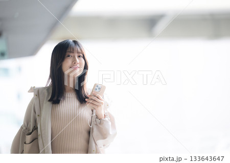 飛行機が背景に見える空港や交通機関のターミナルででスマホを持つ女性の写真 133643647