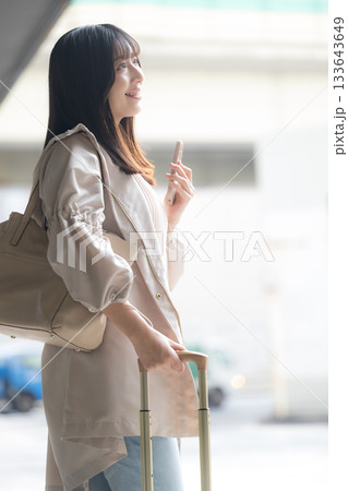 空港や交通機関のターミナルででスマホを持つ女性の写真 旅行や休日のイメージ横顔 空港や交通機関のターミナルででスマホを持つ女性の写真 旅行や休日のイメージ横顔 133643649