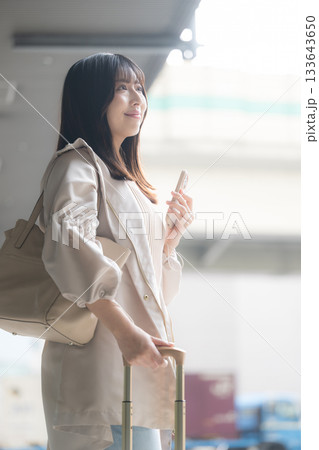 空港や交通機関のターミナルででスマホを持つ女性の写真 旅行や休日のイメージ横顔 空港や交通機関のターミナルででスマホを持つ女性の写真 旅行や休日のイメージ横顔 133643650