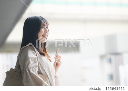 空港や交通機関のターミナルででスマホを持つ女性の写真 旅行や休日のイメージ横顔 空港や交通機関のターミナルででスマホを持つ女性の写真 旅行や休日のイメージ横顔 133643651