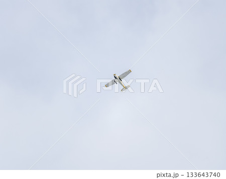 Small ultralight airplane with overhead wing and single propeller flying in sunset sky. Small ultralight airplane with overhead wing and single propeller flying in sunset sky. 133643740