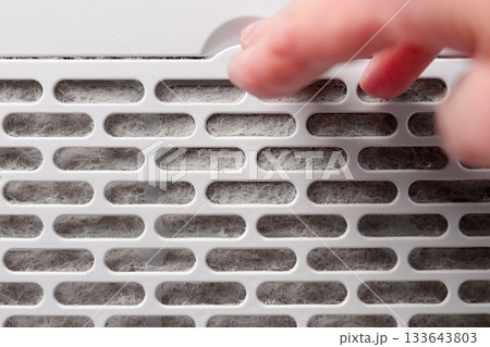 Technician hand removing a dirty dust clogged filter from a home air conditioner appliance 133643803