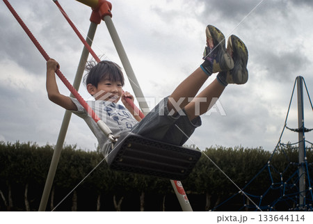 <素材>夕暮れの公園でブランコで遊ぶ少年 <素材>夕暮れの公園でブランコで遊ぶ少年 133644114