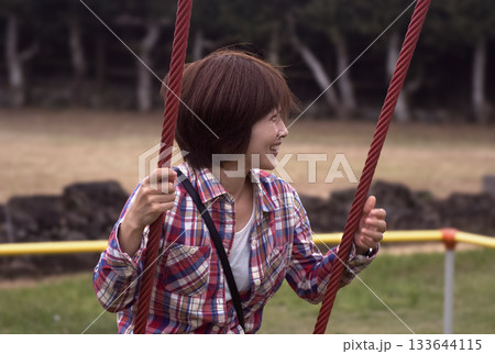 <素材>夕暮れの公園でブランコで遊ぶ女性 <素材>夕暮れの公園でブランコで遊ぶ女性 133644115