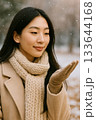 手のひらに雪を受ける女性のポートレート（Woman Catching Snowflakes on H 133644168