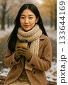 雪の中でホットドリンクを持つ女性（Woman Holding a Hot Drink in the  133644169