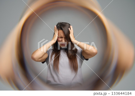 Conceptual image of woman with headache surrounded by blurred tunnel effect 133644184
