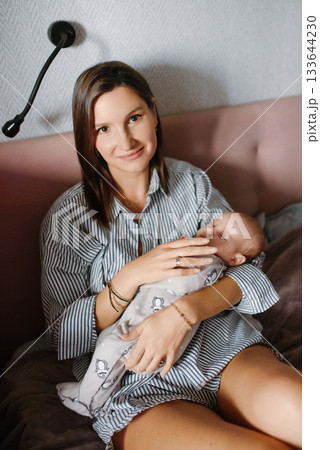Mother Cradling Newborn on Bed 133644230
