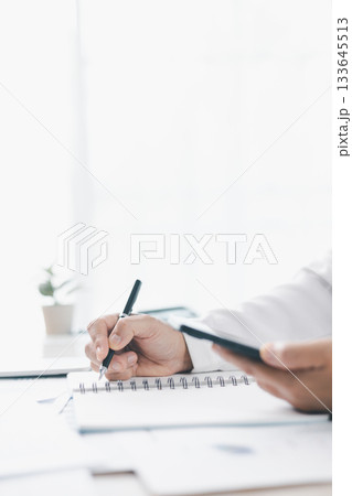 Businessman reviews financial reports, points on chart with pen while analyzing data at office desk working with calculator for accuracy. Concept of accounting, business planning, investment strategy. 133645513