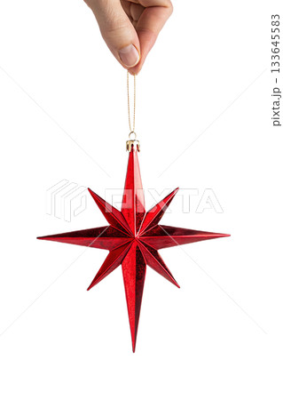 Hand holding shiny, reflective red christmas star ornament against transparent background, symbolizing holiday decoration and festive spirit 133645583