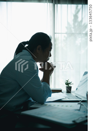 Stressed businesswoman working late at home office, feeling exhausted while reviewing financial documents on laptop. Concept of work stress, burnout, deadline, and overwork. Stressed businesswoman working late at home office, feeling exhausted while reviewing financial documents on laptop. Concept of work stress, burnout, deadline, and overwork. 133645750