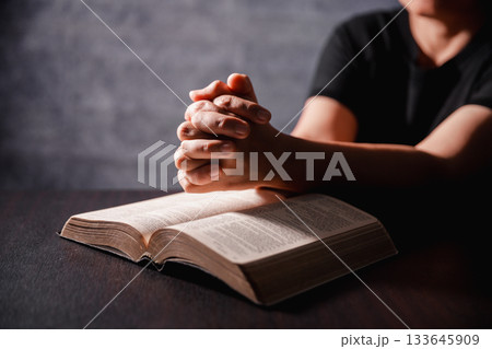 Bible in hand, christian lifts prayer in worship, holding firmly to holy concept of faith, hope and deep belief guides their spiritual life. Hands together in prayer to God along with bible Bible in hand, christian lifts prayer in worship, holding firmly to holy concept of faith, hope and deep belief guides their spiritual life. Hands together in prayer to God along with bible 133645909