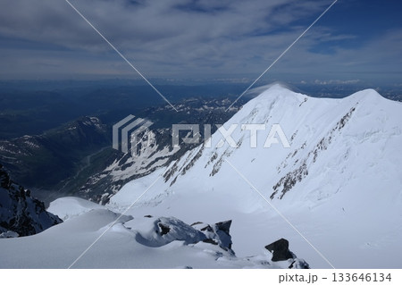 A stunning rock formation covered in snow, set against a clear blue sky with fluffy clouds in the background, creating a peaceful and breathtaking mountain landscape. 133646134