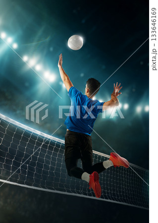Vibrant artwork of male volleyball player jumping for powerful spike above net under arena lights. 133646169