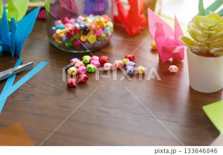 Stars and birds folded from colorful origami paper as a gift or a festive decoration of happiness and hope on a wooden table. with copy space 133646846