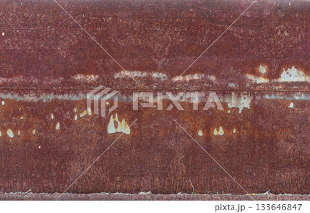 The metal panel is made of iron and has been weathered over time, resulting in a rough and textured surface. The rust has formed in a red color, giving the panel a grunge and industrial feel. 133646847