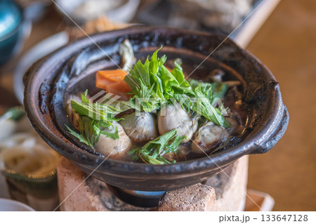Fresh oyster hot pot cooking with vegetables in clay pot on stove 133647128