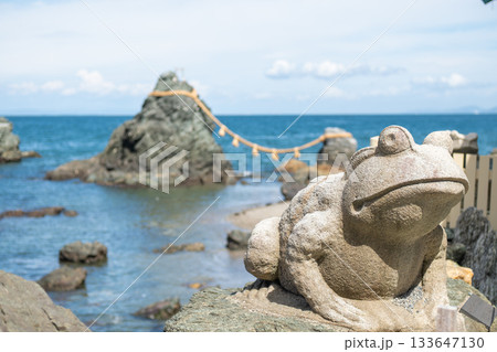 Meoto Iwa Wedded Rocks near Futami, Ise city, Japan, Stone frog statue near rocky coast with ocean and rope bridge in background Meoto Iwa Wedded Rocks near Futami, Ise city, Japan, Stone frog statue near rocky coast with ocean and rope bridge in background 133647130