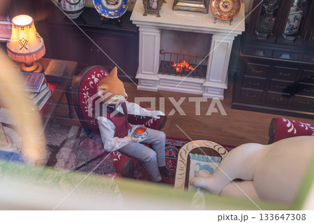 Ghibli Park, Aichi, Nagakute, Ibaragabasama, Japan - Sep 19, 2024 : Person wearing fox mask sitting in living room with cup near fireplace Ghibli Park, Aichi, Nagakute, Ibaragabasama, Japan - Sep 19, 2024 : Person wearing fox mask sitting in living room with cup near fireplace 133647308