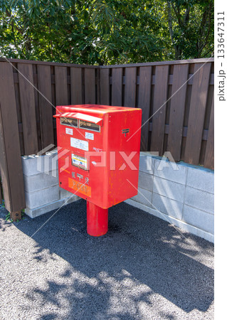 Ghibli Park, Aichi, Nagakute, Ibaragabasama, Japan - Sep 19, 2024 : Red mailbox standing on pavement near wooden fence outdoors 133647311
