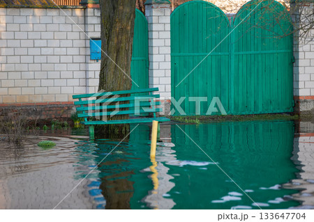 Spring flood. The gate of the house and the bench are flooded with water. Spring flood. The gate of the house and the bench are flooded with water. 133647704