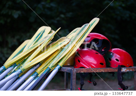 Boat oars and red helmets for rafting. Active recreation during the trip Boat oars and red helmets for rafting. Active recreation during the trip 133647737