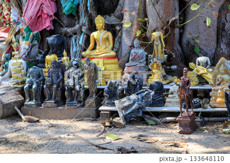 A crumbling and broken Buddha statue with golden figures at an outdoor Buddhist shrine. 133648110