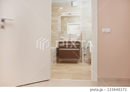 Modern bathroom featuring a vanity, sink, mirror, and tiled walls seen through an open door Modern bathroom featuring a vanity, sink, mirror, and tiled walls seen through an open door 133648172