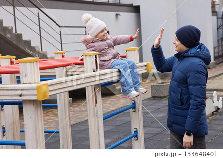 Father and daughter bonding, giving a high five, and playing outdoors during winter Father and daughter bonding, giving a high five, and playing outdoors during winter 133648401