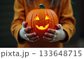 Child's Mummy Hands Holding Friendly Smiling Jack-o-Lantern Pumpkin 133648715