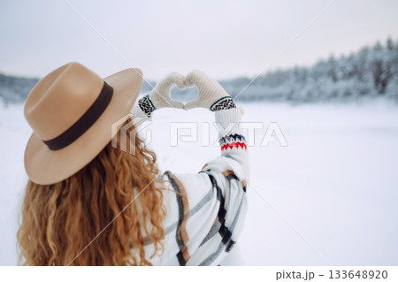 Women's hands in mittens symbolize a heart against the backdrop of a winter landscape. Lifestyle 133648920