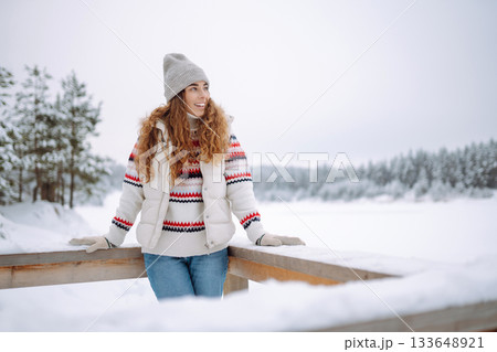 Beautiful young woman in winter clothes enjoying the winter forest. Christmas. Beautiful young woman in winter clothes enjoying the winter forest. Christmas. 133648921