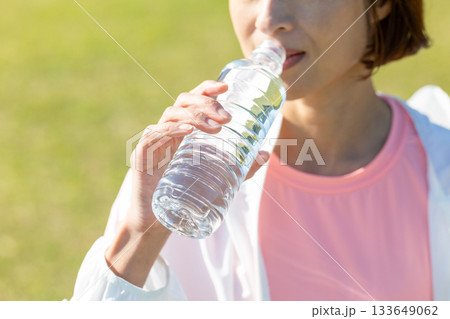 屋外で運動後にペットボトルの水を飲むミドル女性 133649062