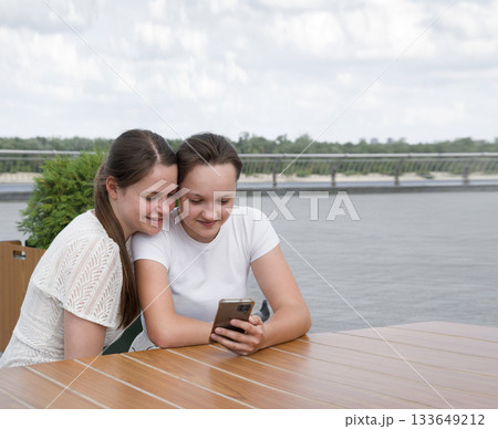 Two girls using a phone Two girls using a phone 133649212