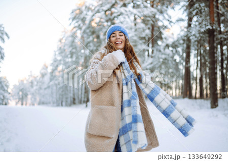 Young woman in warm clothes plays with snow on a sunny winter day. Concept of walking, fun. Young woman in warm clothes plays with snow on a sunny winter day. Concept of walking, fun. 133649292