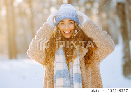 Laughing beautiful woman in the winter forest enjoying an amazing sunset. Walking concept. 133649327