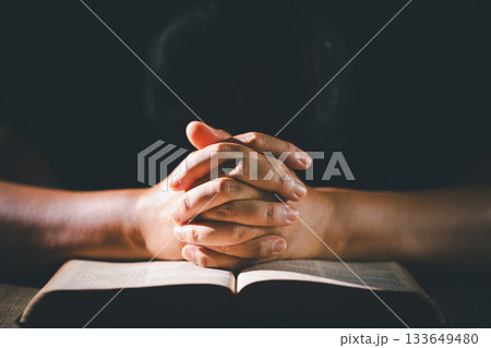 Hands clasped in prayer over the holy Bible, the faithful Christian worships God in church, holding onto hope and belief, guided by religion and a deep commitment to their religious faith. 133649480