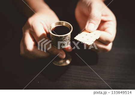 Hands holding communion bread with a wooden bowl and wine cup, symbolizing Holy Communion, the Eucharist, the sacrifice of Jesus Christ and Christian faith in the Lord Supper. 133649514