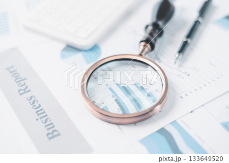 Magnifying glass with calculator and pen on financial reports with charts, graphs at office desk. Concept of business analysis, accounting audit, financial accuracy, transparency, corporate strategy. Magnifying glass with calculator and pen on financial reports with charts, graphs at office desk. Concept of business analysis, accounting audit, financial accuracy, transparency, corporate strategy. 133649520