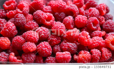handful of fresh raspberries lying in a container, red ripe berries containing vitamins, with a wonderful aroma, raspberries for sale at the market, a tray with berries close-up, raspberry background 133649731