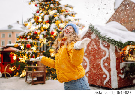 A woman in a bright jacket and red lips walks through a Christmas market and drinks a hot drink. A woman in a bright jacket and red lips walks through a Christmas market and drinks a hot drink. 133649822