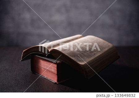 Open Bible on black background. Religion concept. a Christian sat reading an open Bible the holy book of Christianity deepening their faith in God and Jesus Christ, the foundation of their religion. 133649832